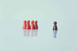 Plastic figures representing a group of people with one person separated, representing mandatory quarantine