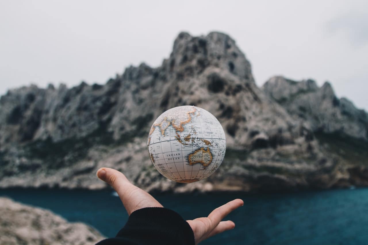 A hand tossing a small globe, representing where Canadians can travel during COVID