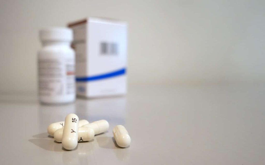 A prescription pill bottle and pills representing medication Americans travel to Canada to obtain