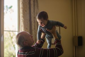 An elderly man holding his grandchild represent new compassionate exemptions to the border closure