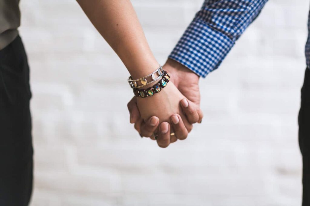A man and woman holding hands representing a conjugal relationship between a gay man and straight woman for immigration purposes