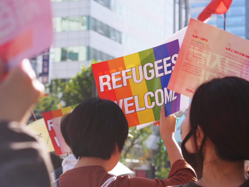 A woman holding a sign that says Refugees Welcome