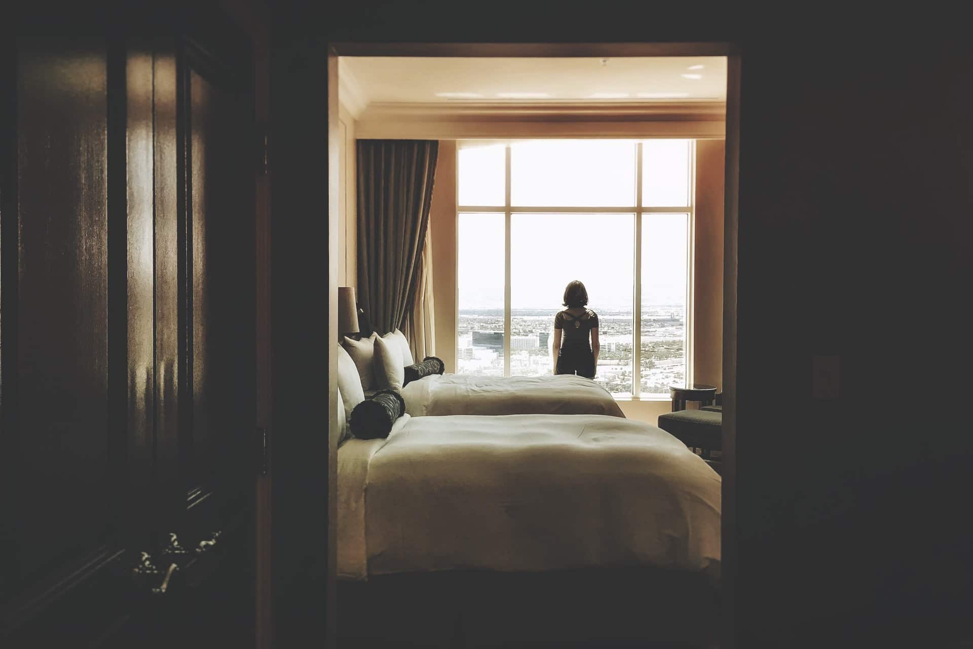 Woman at hotel window representing recommendations that Canada end hotel quarantine