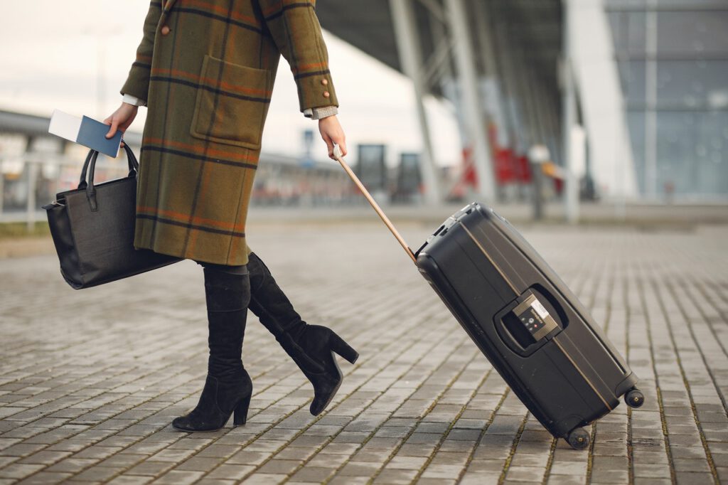 A woman walking with travel documents and a suitcase representing Canada implementing vaccine passports for international travel.