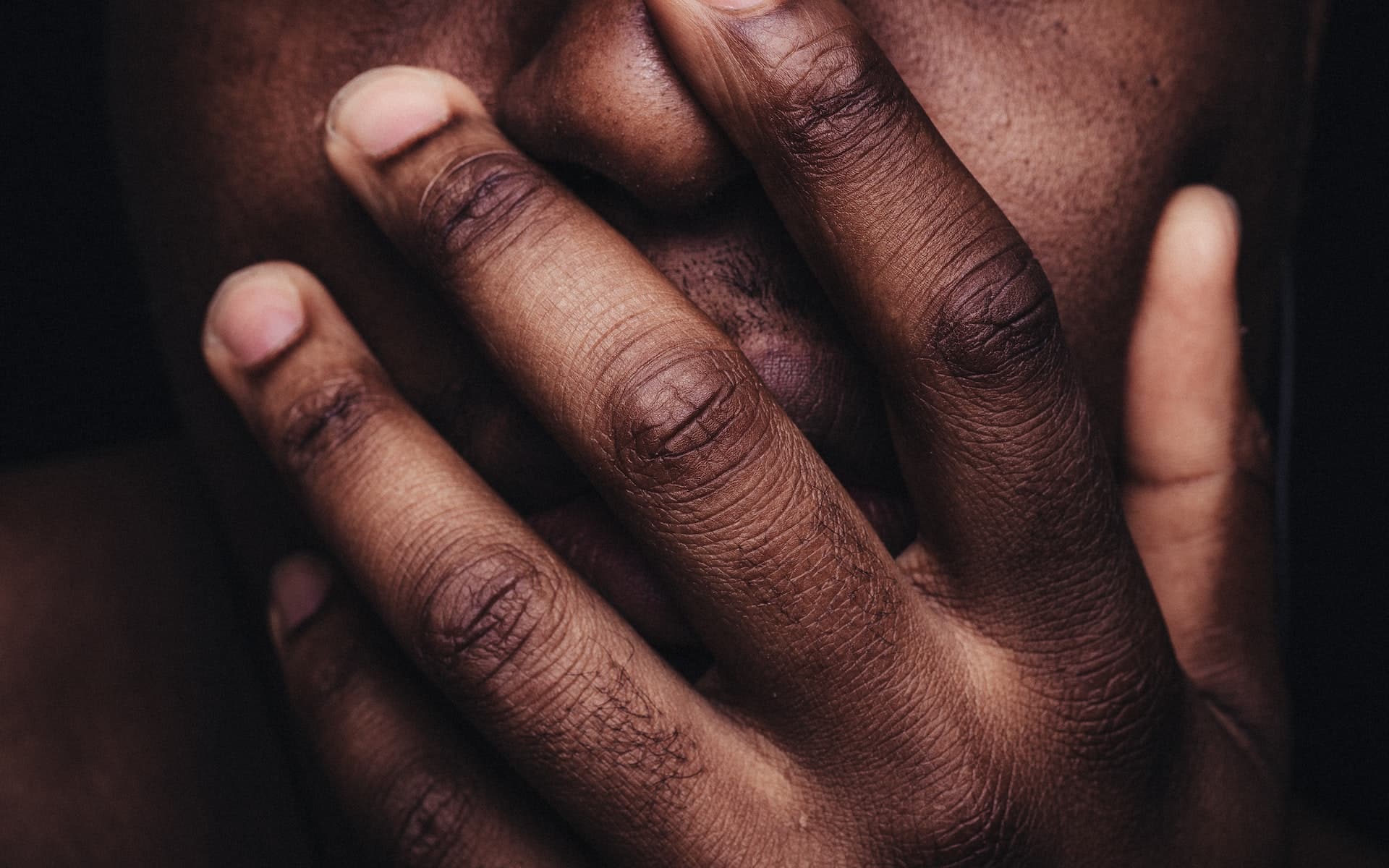 a black person holding hand to face