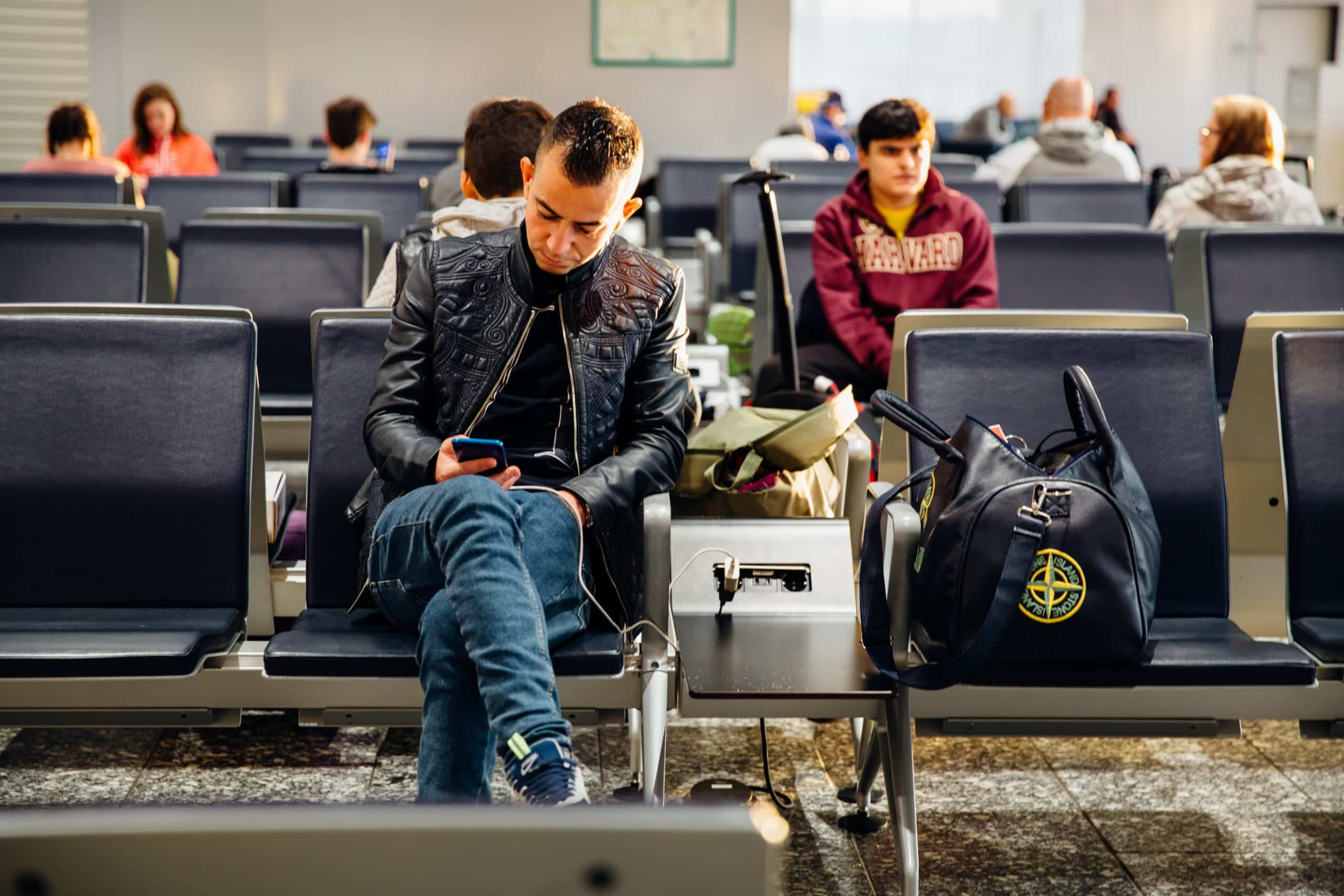 Man sitting at airport representing changes to travel restrictions, arrivecan and vaccinations