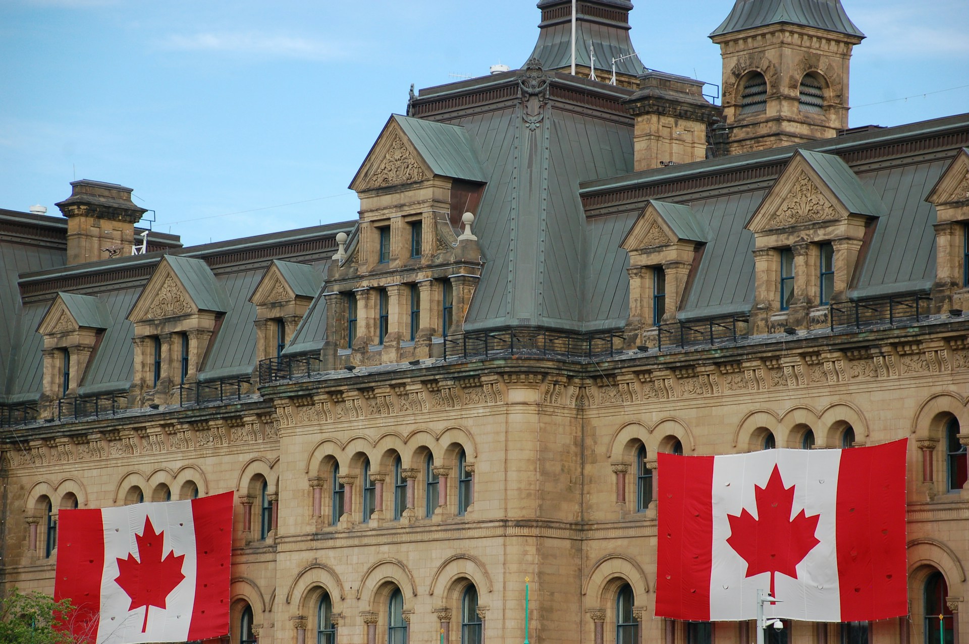Two Canadian flags are mounted on the Parliament building, representing 2025 Canadian Federal Election.