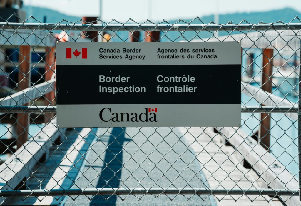 A chain link fence with a Canada Border Inspection sign, representing Bill C-2 and the Strong Borders Act