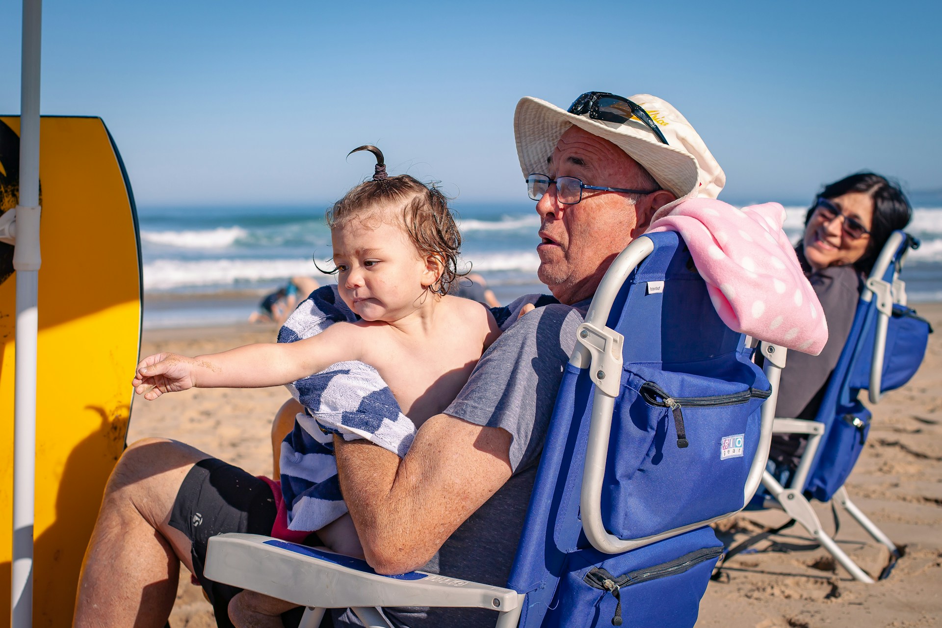 a man sitting in a chair on a beach with a young child in his lap