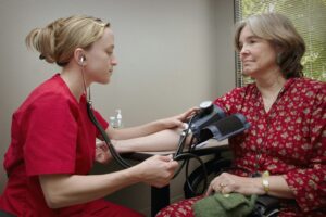 A female doctor adminstering a blood pressure test to a female patient, representing medical exam and language exam requirement for Permanent Resident status in Canada
