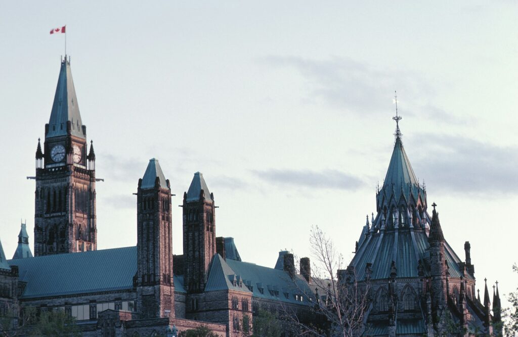 The roofline of the Canadian Parliament buildings against a faded blue sky, representing Canada's 2026 Category-Based Express Entry.