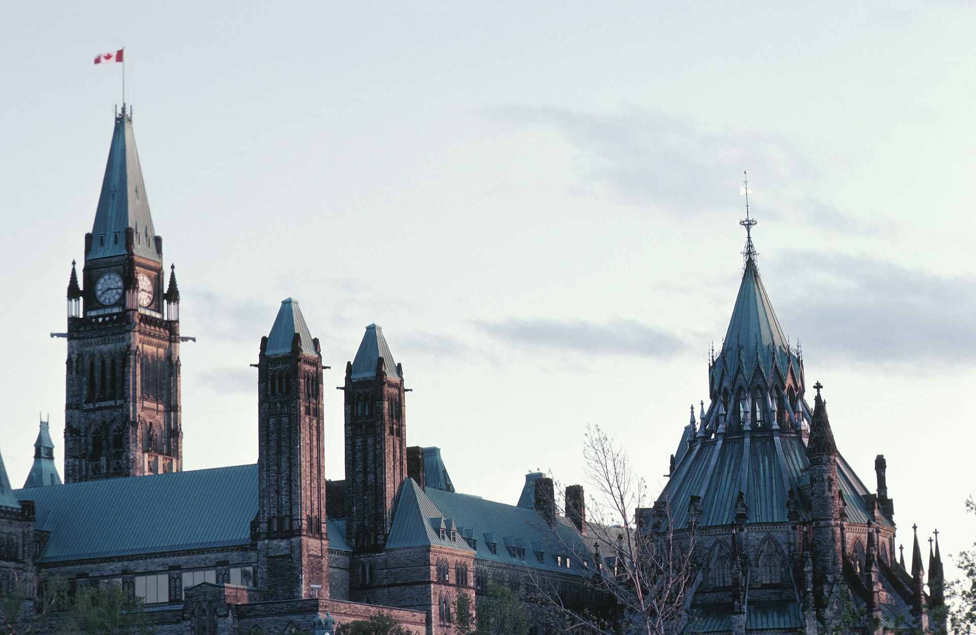 The roofline of the Canadian Parliament buildings against a faded blue sky, representing Canada's 2026 Category-Based Express Entry.
