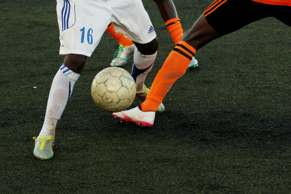 Three soccer players, shown from the waist down, try to kick the soccer ball away from the others, representing FIFA World Cup.