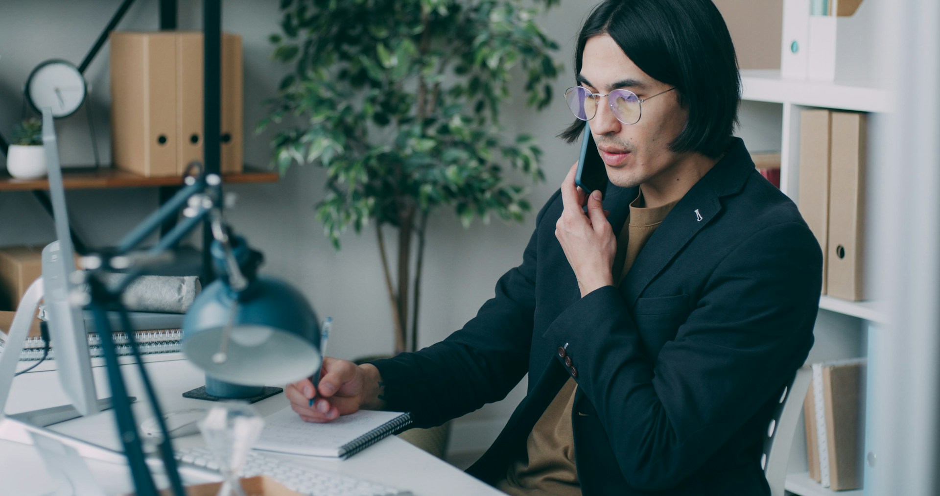 A young professional working at his desk while talking on a phone, representing Canadian immigration requirements and the 2026 Express Entry changes in Canada.