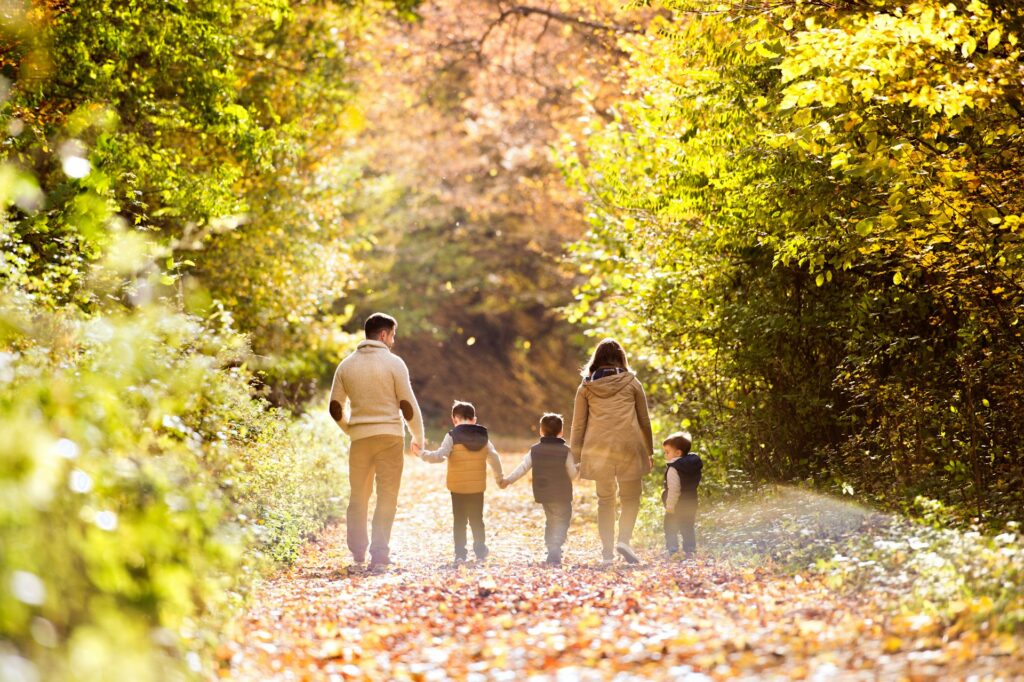 A family with young children walking down a brightly lit forest path in autumn, representing Canadian citizenship and the 2026 suspensions on Citizenship by Descent applications.
