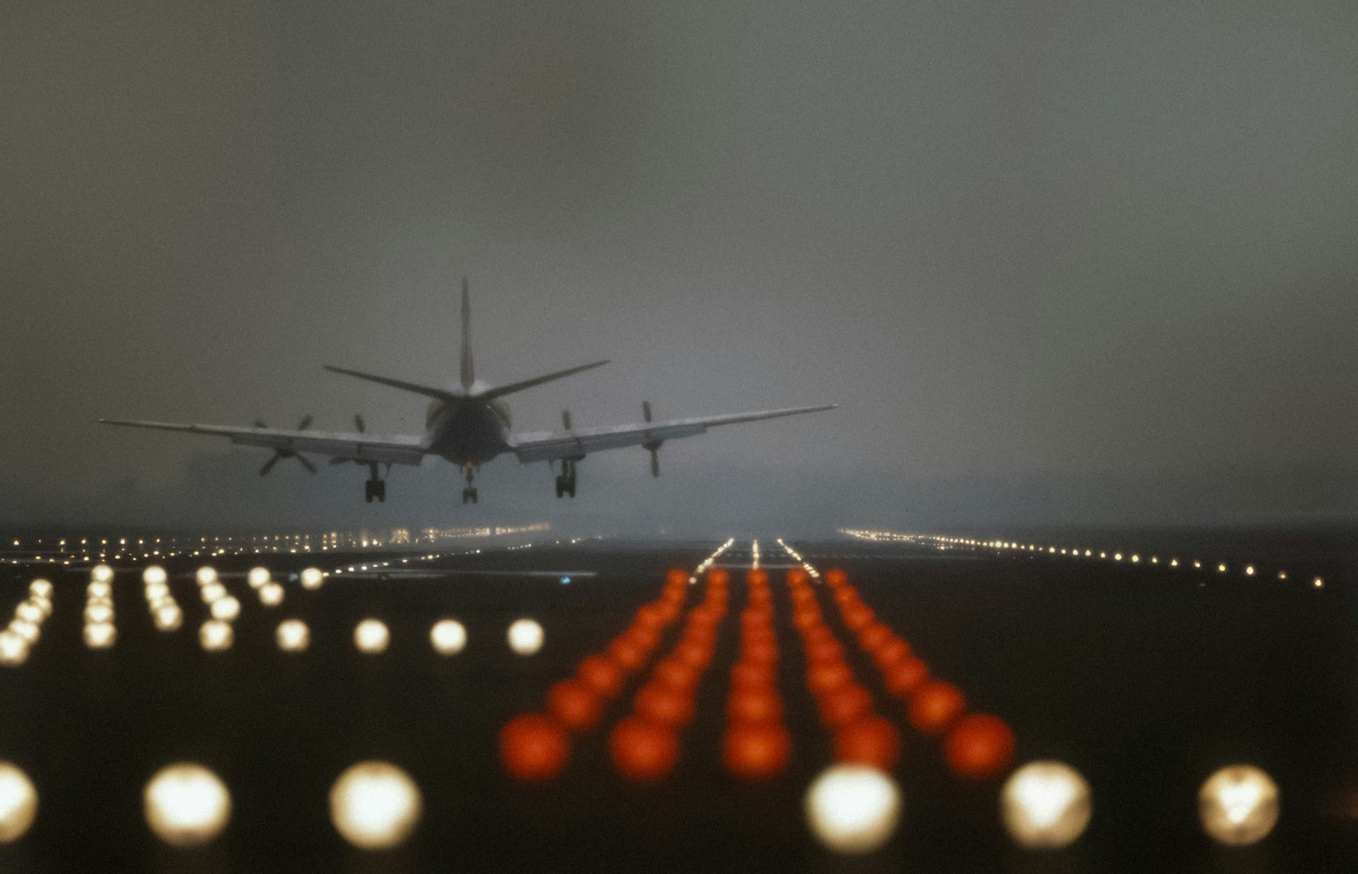 A plane lands on a foggy runway lit up with white and red lights, representing Express Entry.