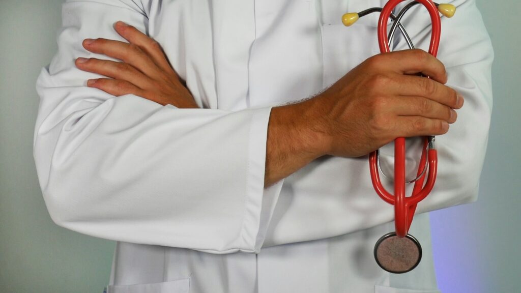 A male physician holding a stethoscope, with his arms crossed over his chest, representing the Physicians Stream and implementation of the Ontario Immigrant Nominee Program (OINP).