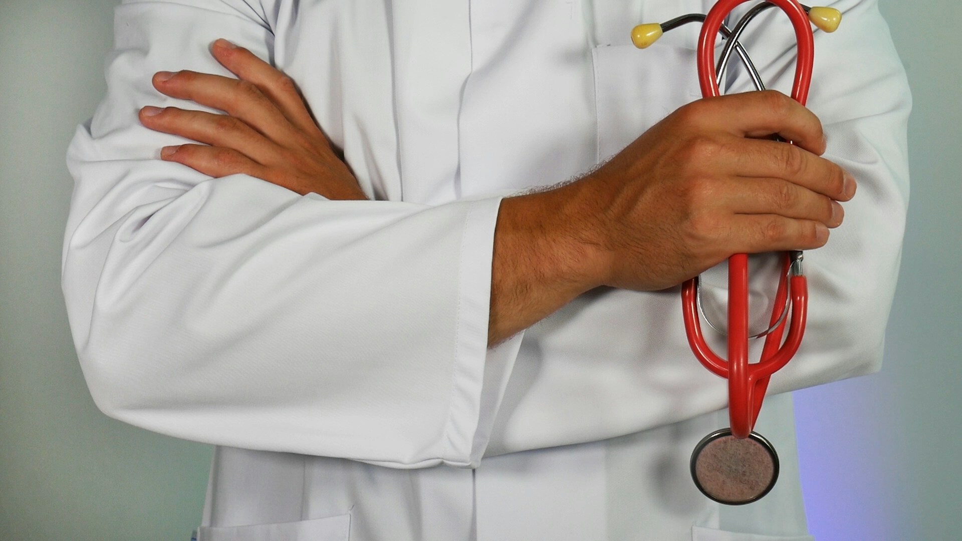 A male physician holding a stethoscope, with his arms crossed over his chest, representing the Physicians Stream and implementation of the Ontario Immigrant Nominee Program (OINP).